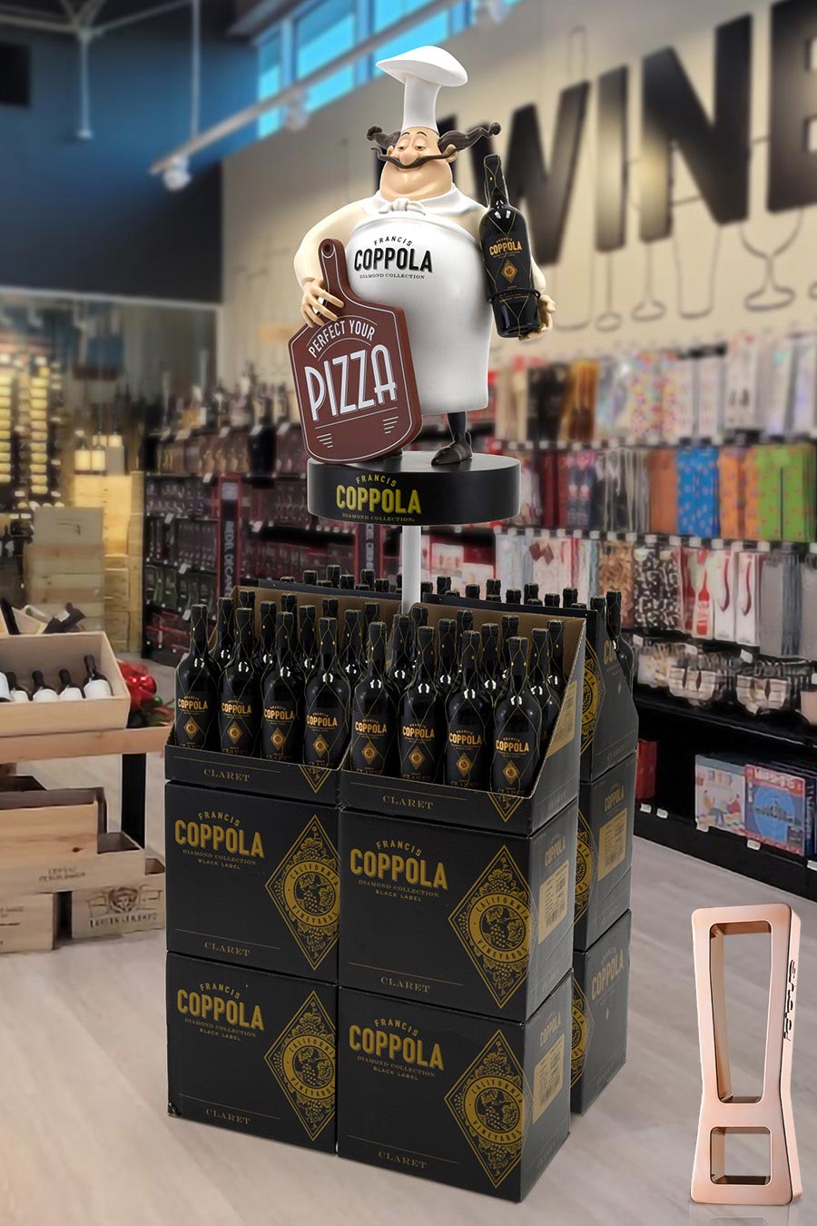 A life-size chef statue holding a wine bottle and a 'Perfect your pizza' sign atop a pyramid of Coppola wine boxes in a retail store backdrop.